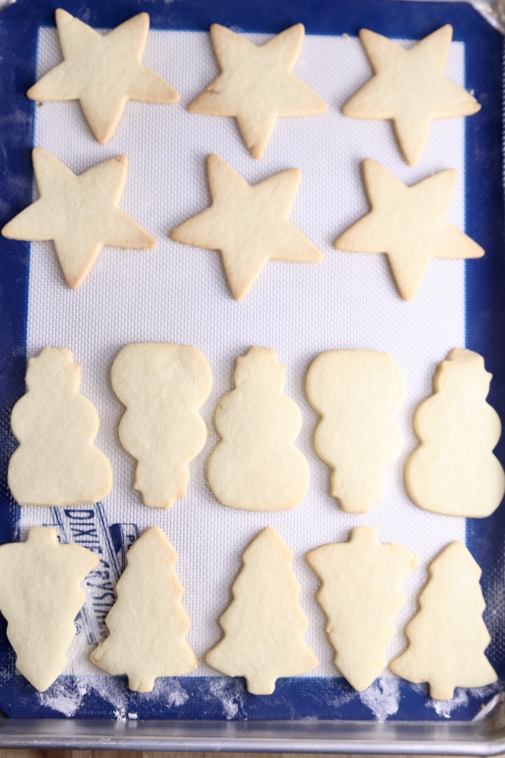 Baked Cut out sugar cookies on a baking sheet. Stars, snowmen and trees.