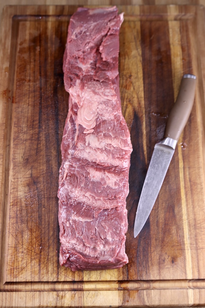 Trimmed Beef Tenderloin on a cutting board with a knife