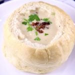 Bread bowl of beer cheese soup topped with bacon and parsley