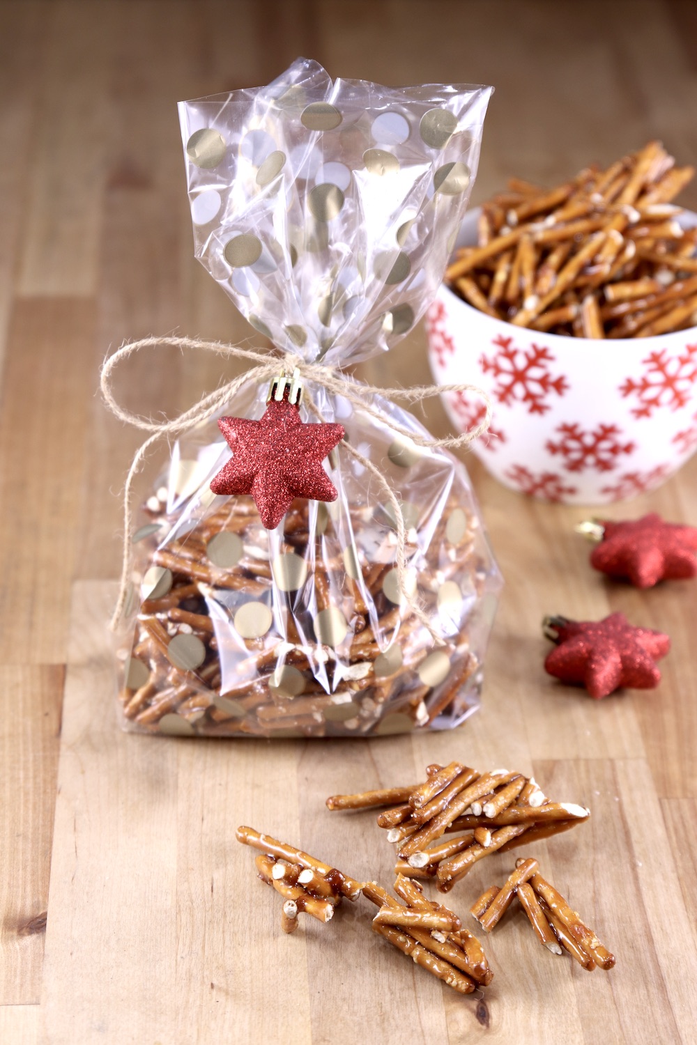 Cellophane bag of candied pretzels tied with string and a red star ornament. A few pretzels on the counter
