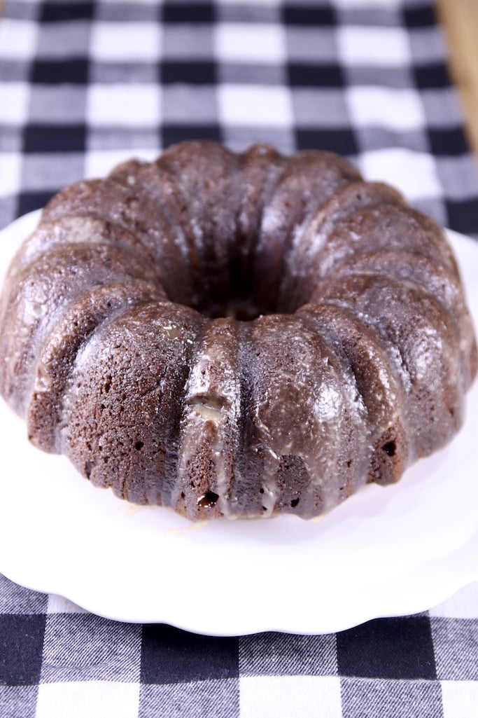 Chocolate Rum Bundt Cake with Buttered Rum Glaze on a serving plate on a black and white check runner