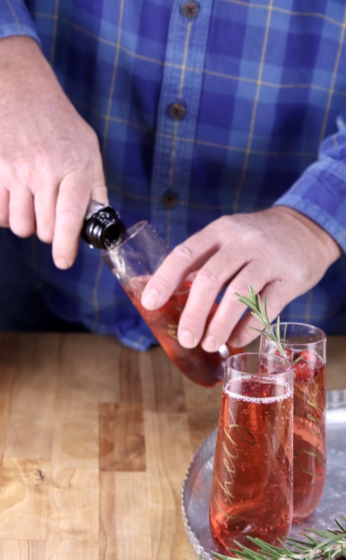 Man filling a champagne flute with sparkling wine for mimosa