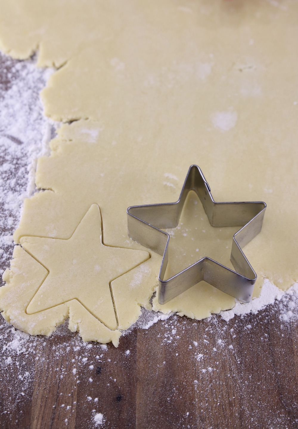 Cookie dough rolled out cutting out with a star cookie cutter