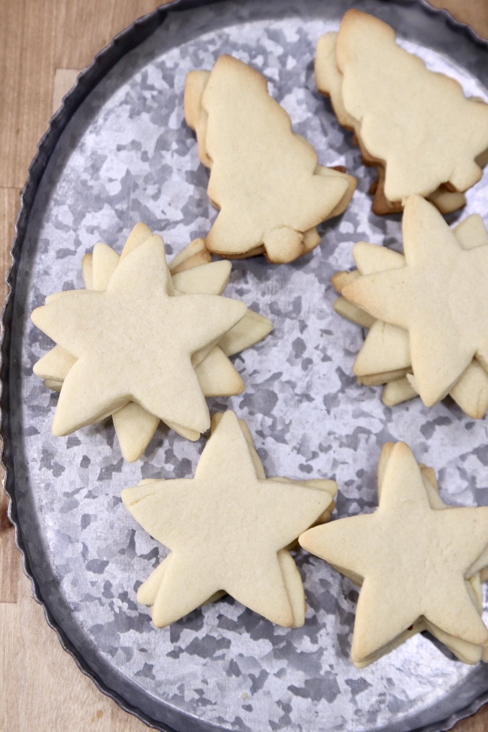 Tray of cut out sugar cookies stacked. Stars and tree shapes.