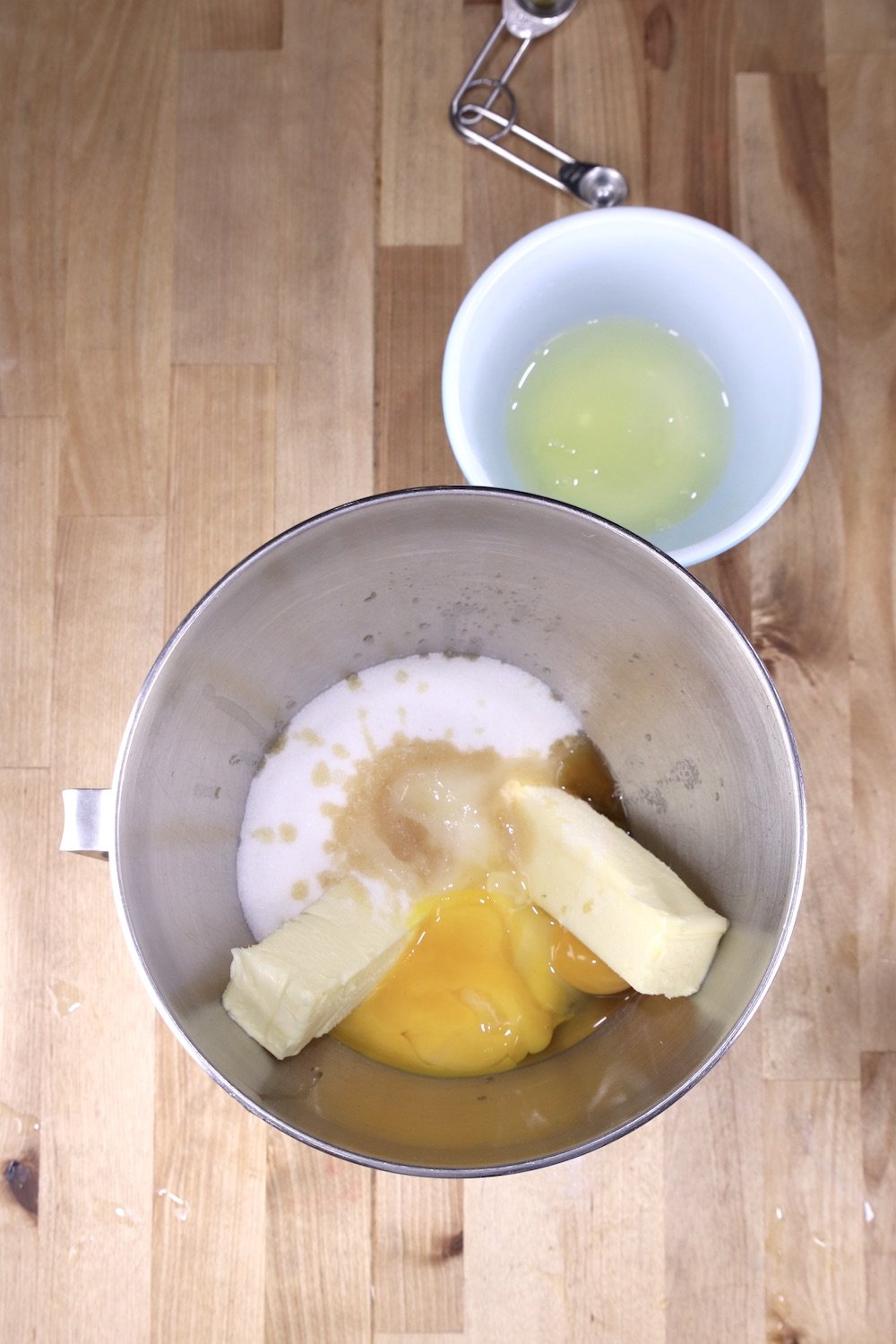 Mixer bowl with butter, sugar, vanilla & eggs, bowl of egg whites to the side