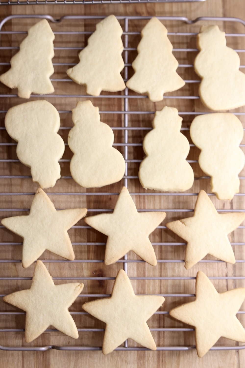 Wire rack of cut out sugar cookies. Trees, snowmen, stars.