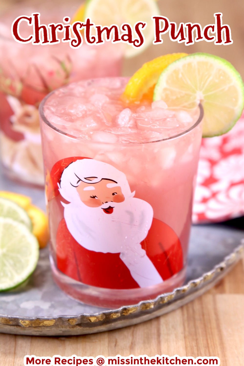 Christmas Punch in a Santa glass with orange and lime garnish - text overlay