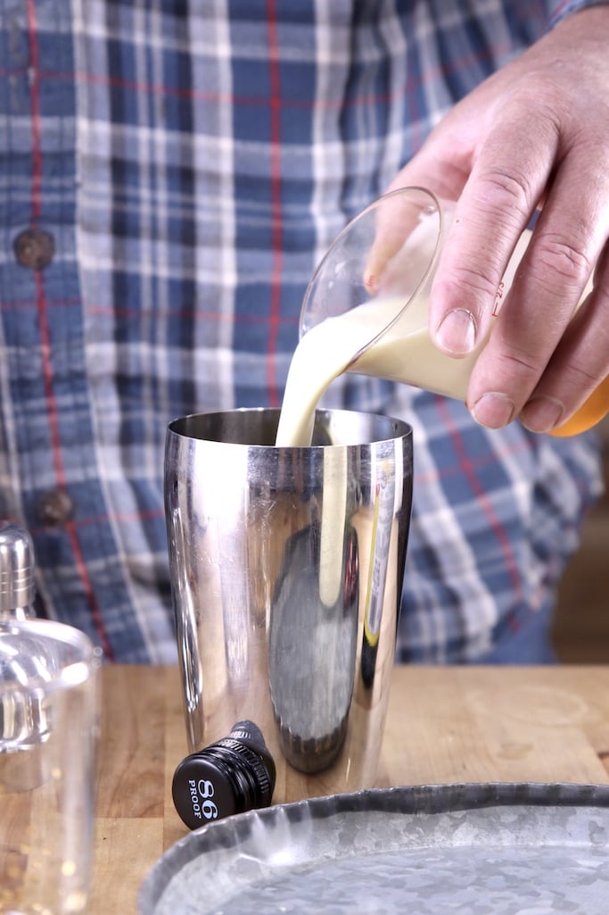 Making an eggnog cocktail with bourbon in a cocktail shaker