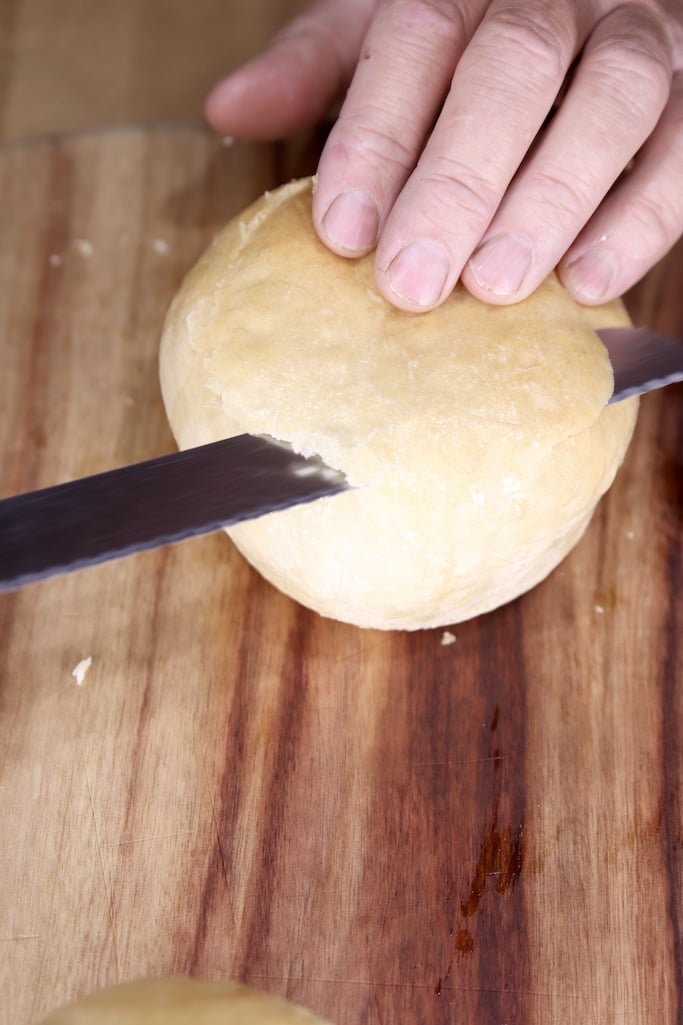 Slicing the tops of bread bowls with a bread knife