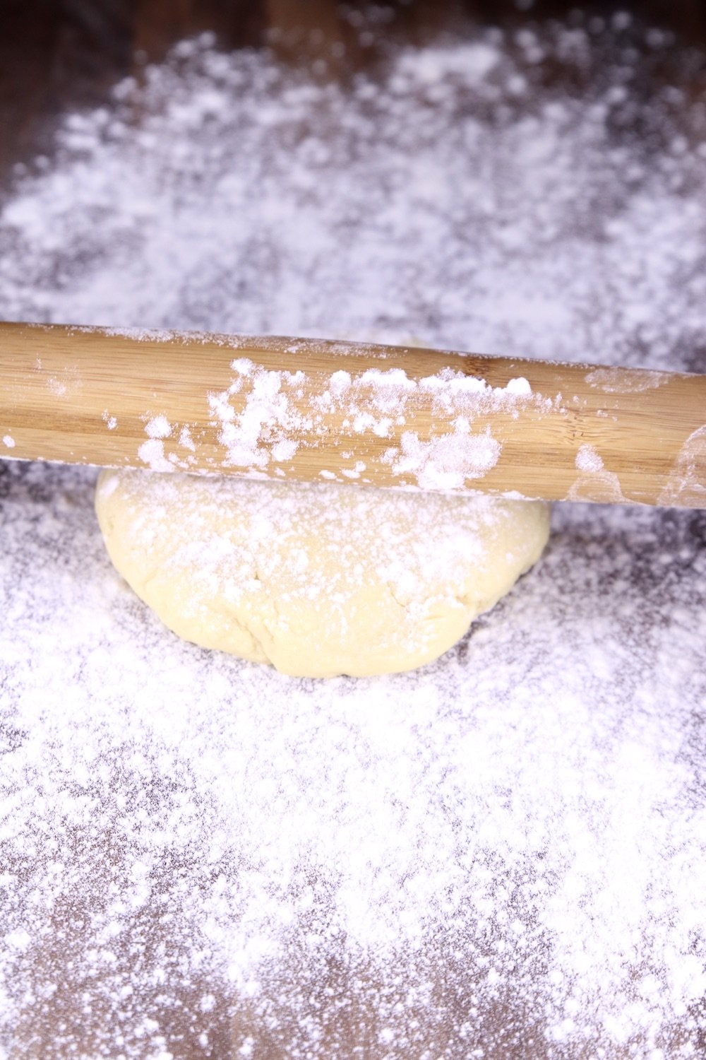 Rolling pin rolling sugar cookie dough on a well floured board
