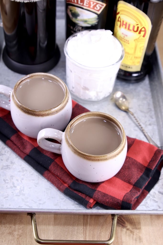 2 coffee mugs with mudslide coffee on a tray with whipped cream in a jar