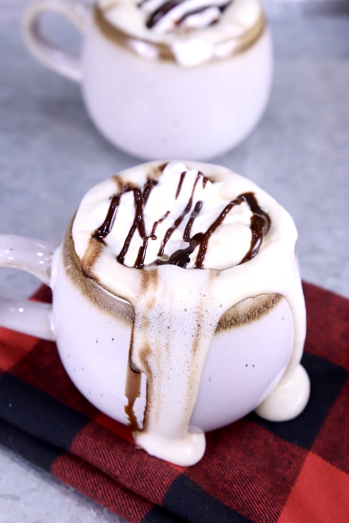 Mug of Mudslide coffee with whipped cream and chocolate sauce, overflowing onto the red napkin