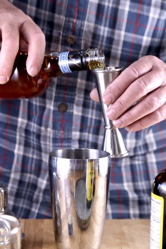 Pouring bourbon into a jigger for cocktails