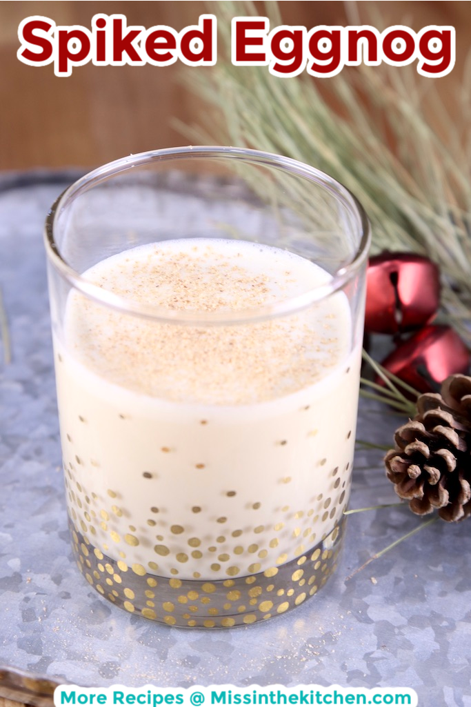 Spiked Eggnog with text overlay - Christmas greenery and red jingle bells to the side of the tray