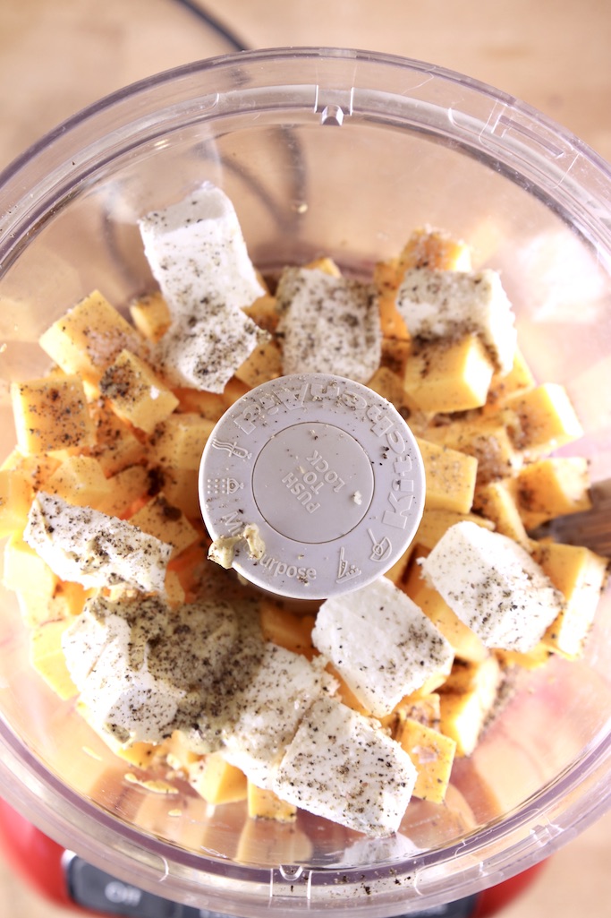 Food processor with chunks of cream cheese, cheddar cheese and spices