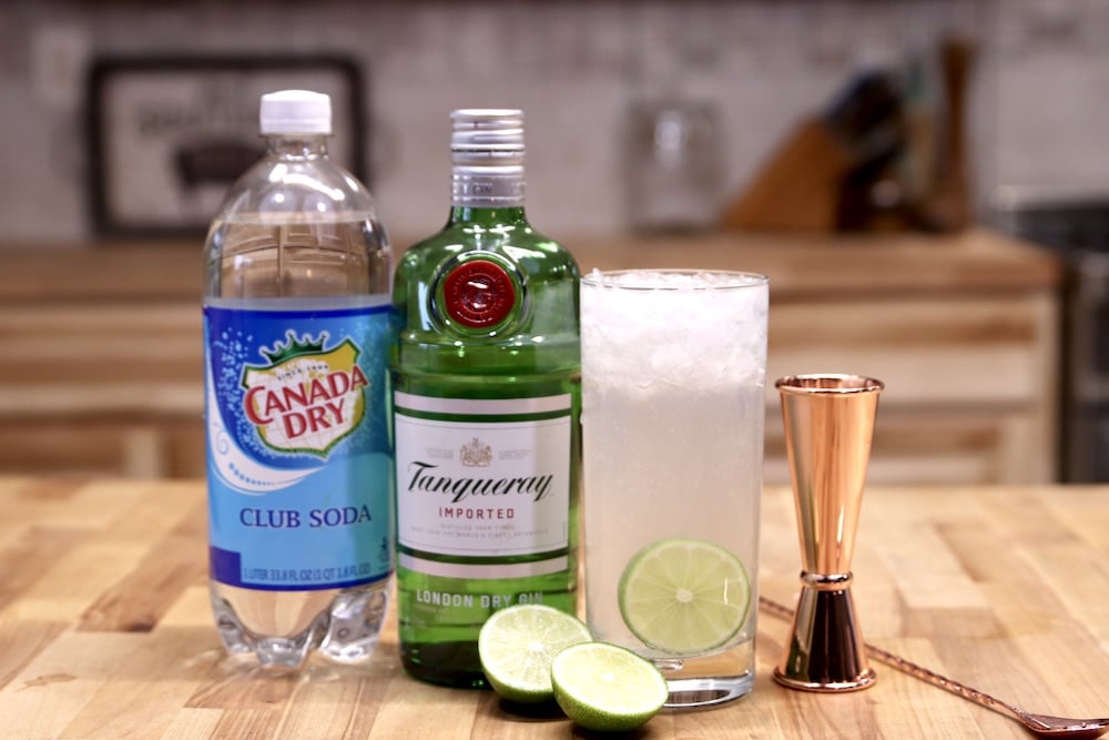 Ingredients for Gin Rickey Cocktail: club soda, gin, limes, with the cocktail