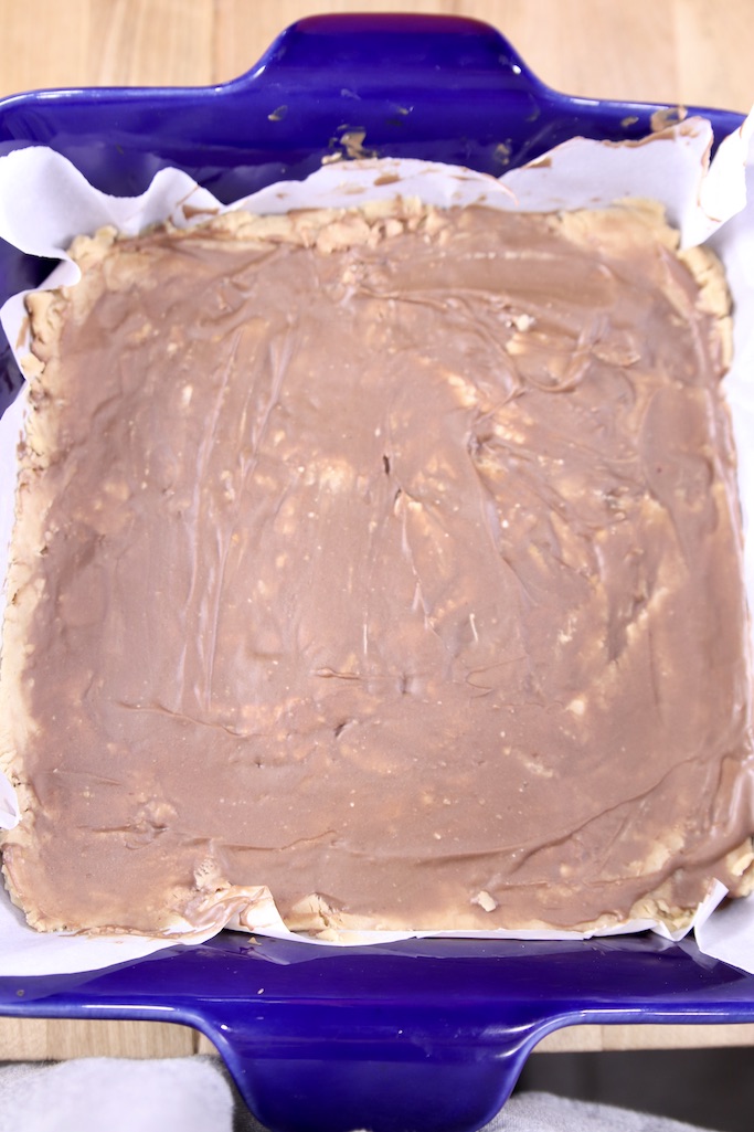 Chilled peanut butter cup fudge with chocolate on top in a blue baking dish