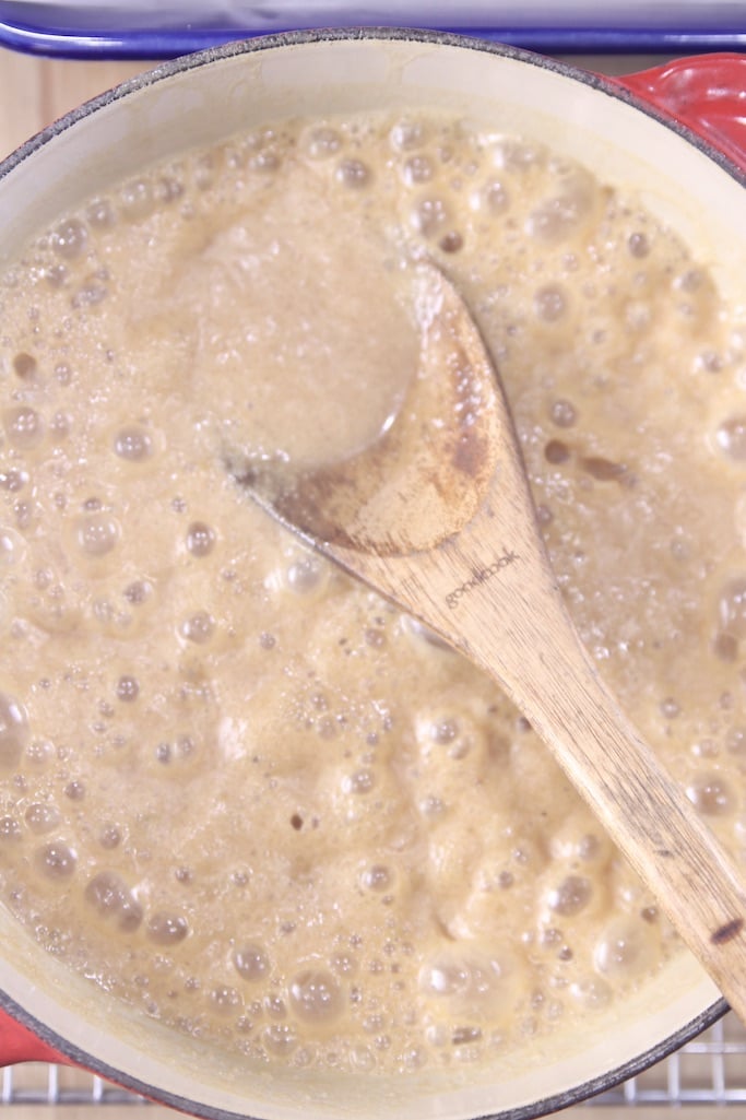 Boiling peanut butter and butter mixture in a pan with a wood spoon