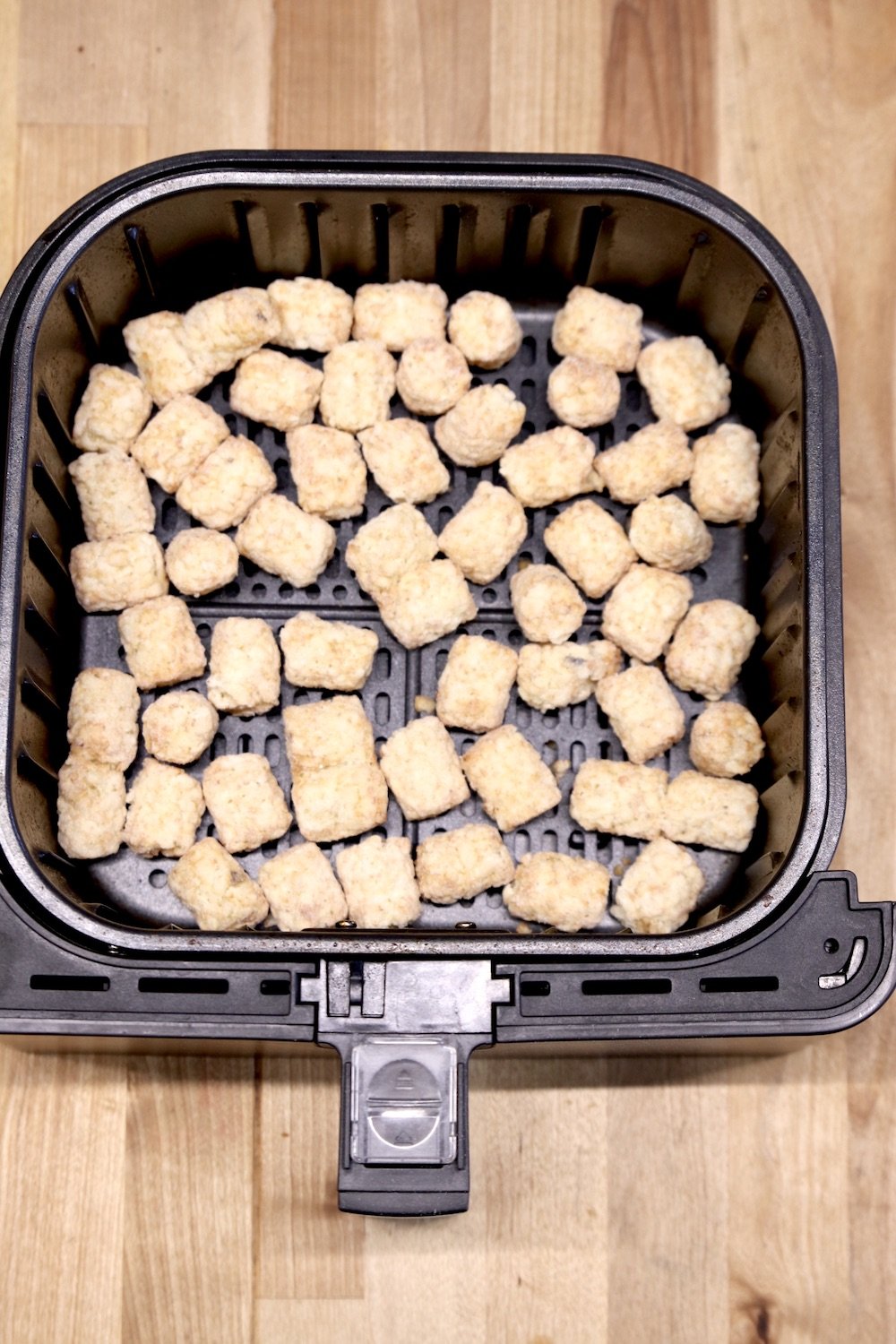 Air fryer basket with frozen tater tots 