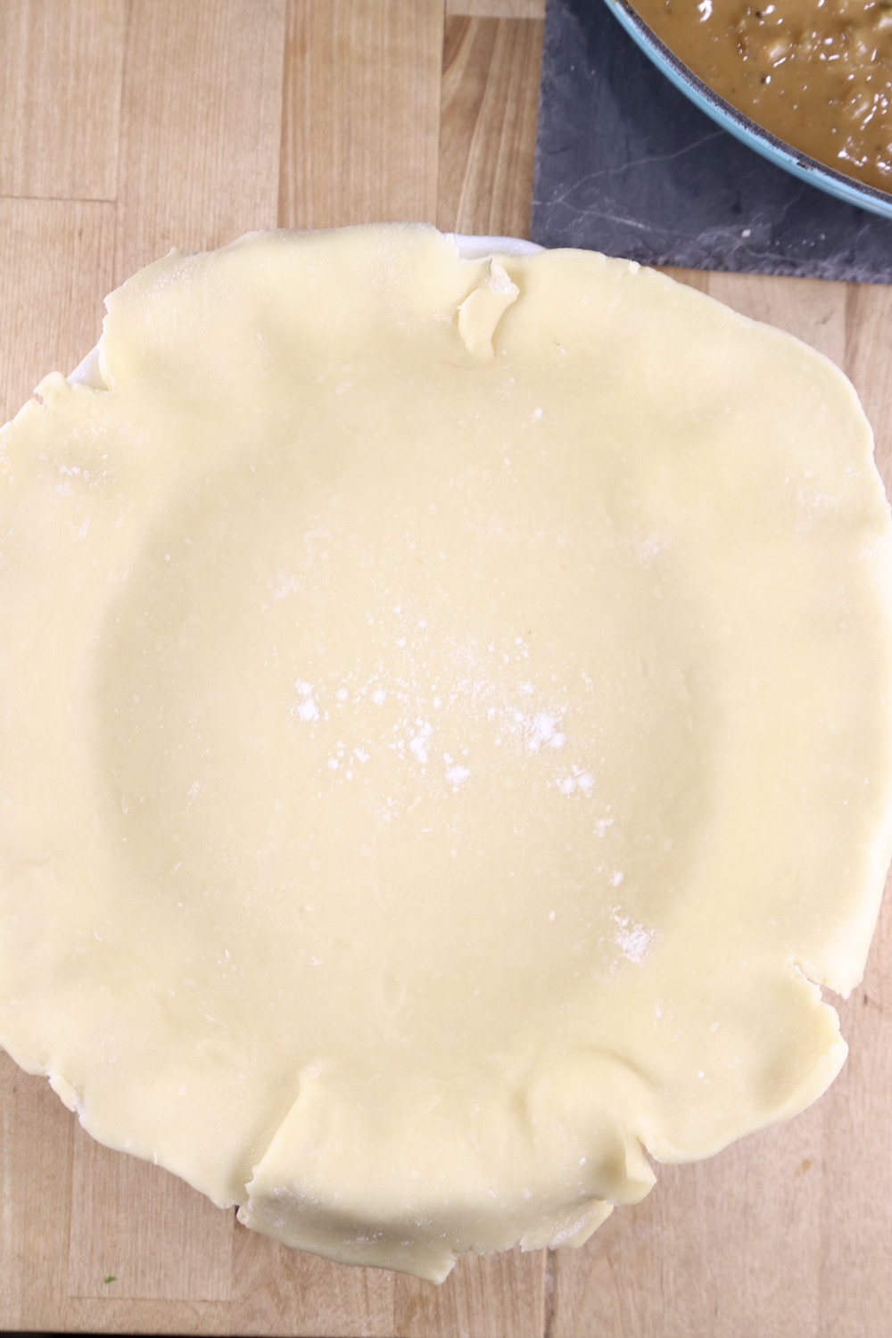 pie crust in a pie plate, edges draped over pie plate