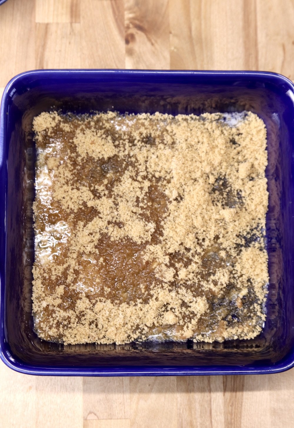 brown sugar and melted butter in a square blue baking dish for pineapple upside down cake