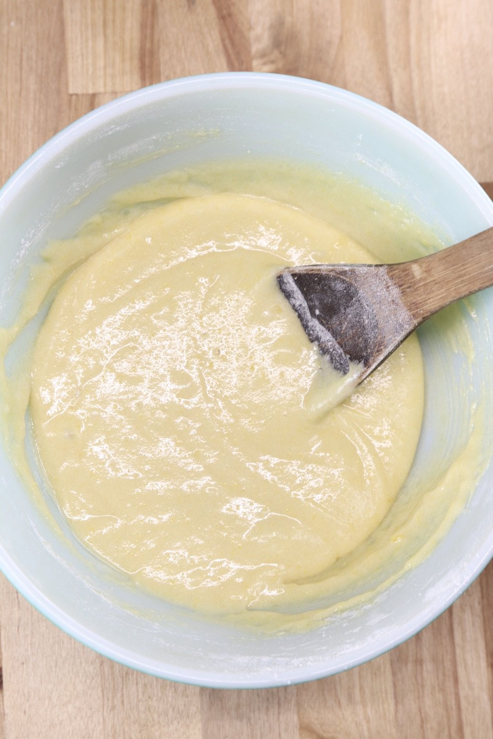 Batter for Pineapple upside down cake in a bowl with wood spoon