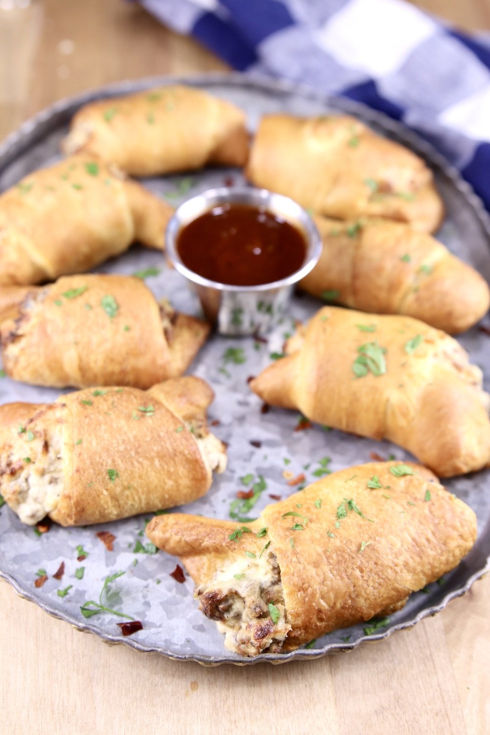Platter of sausage filled crescents with bbq dipping sauce in center