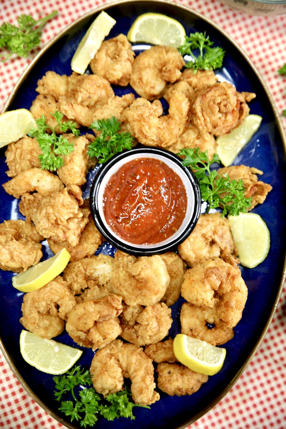 Platter of fried shrimp with lemon wedges, parsley and cocktail sauce.