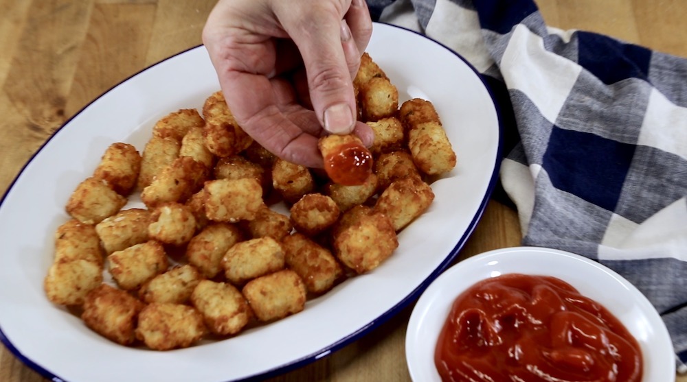 platter of tater tots with one dipped in ketchup