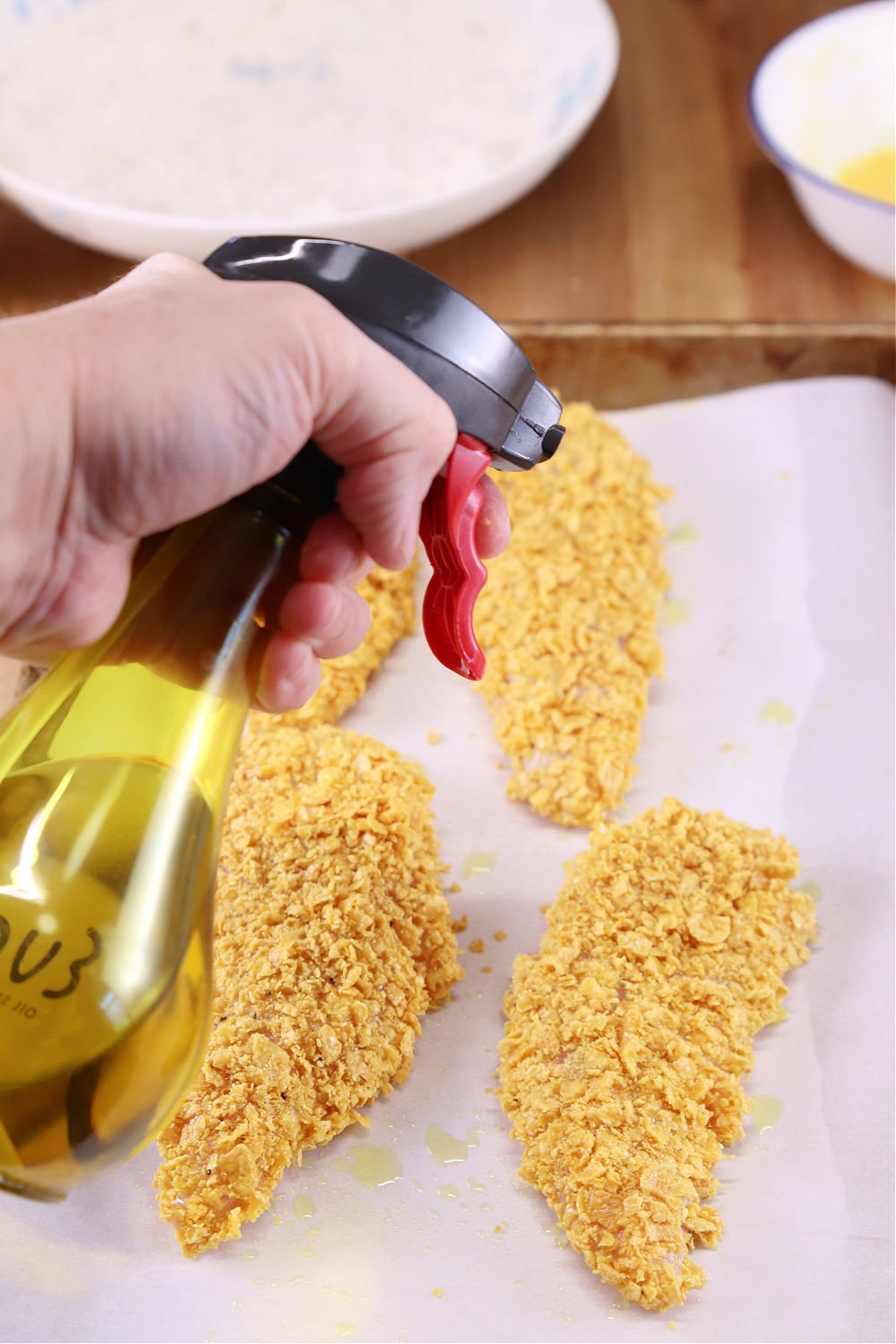 spraying chicken tenders with olive oil