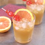2 amaretto sour cocktails garnished with cherries and orange slices
