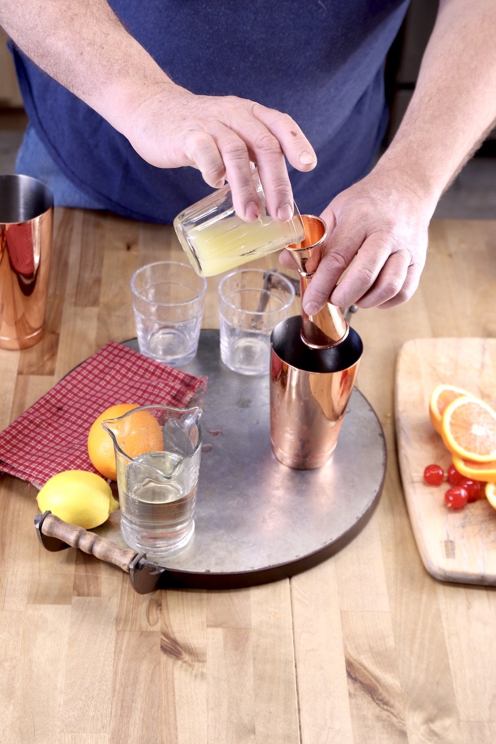 pouring lemon juice into a jigger for cocktails