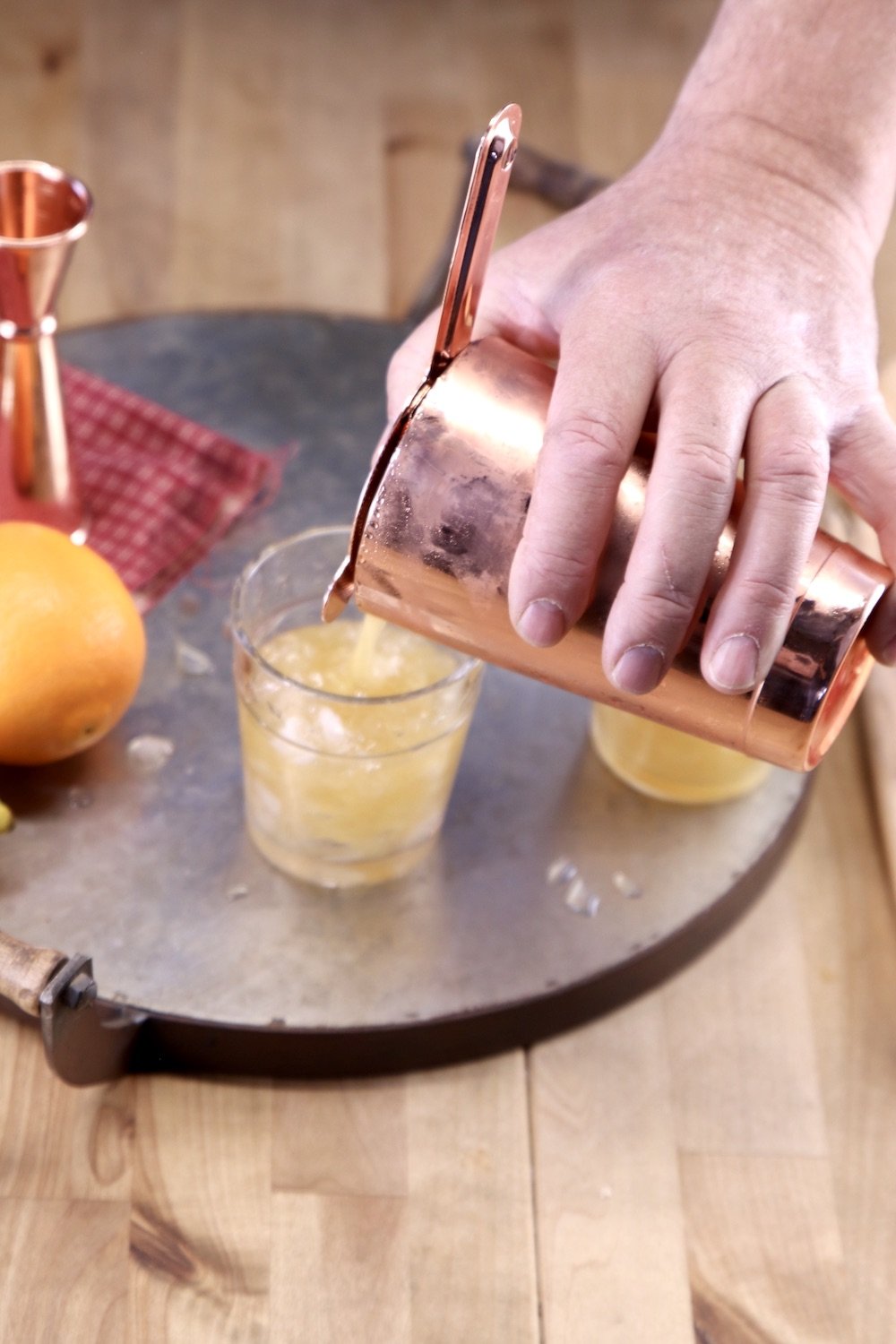Man pouring Amaretto Sour Cocktail into a glass from shaker