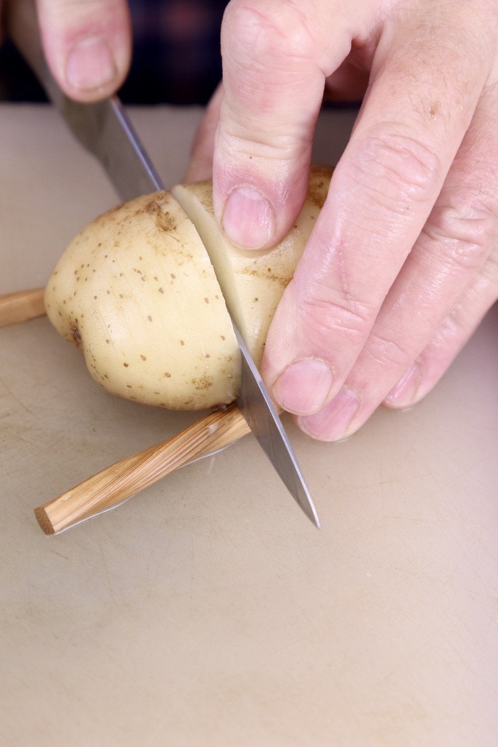 Cutting a potato in thin slices - potato resting between chop sticks