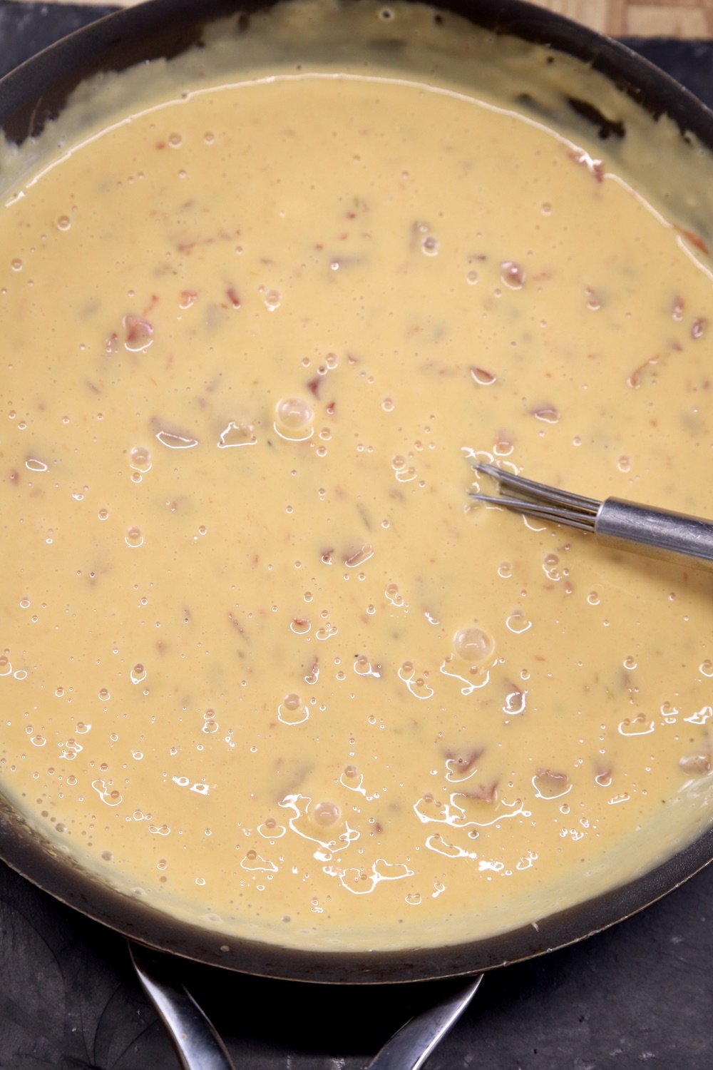 skillet of Velveeta Cheese Dip with a whisk in the pan