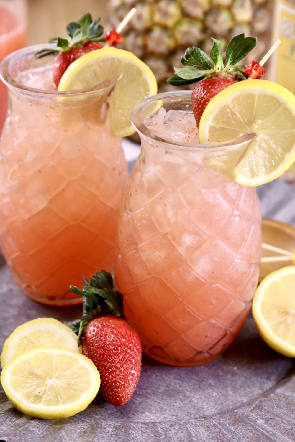 Pineapple Vodka Strawberry Lemonade Cocktails in tiki glasses with lemon garnish