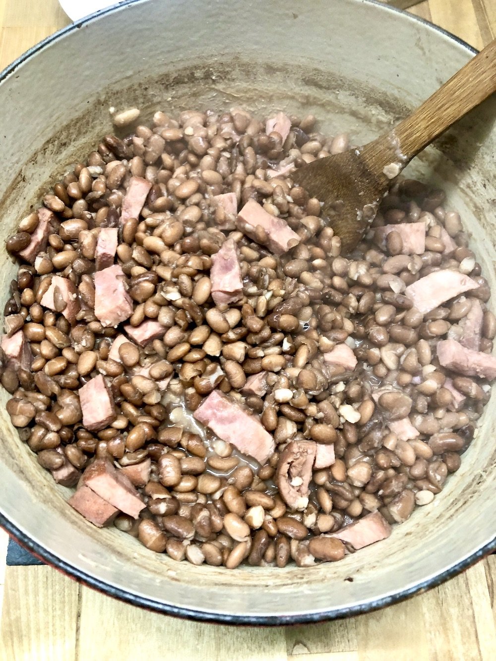 Pinto Beans with ham in a dutch oven with wooden spoon