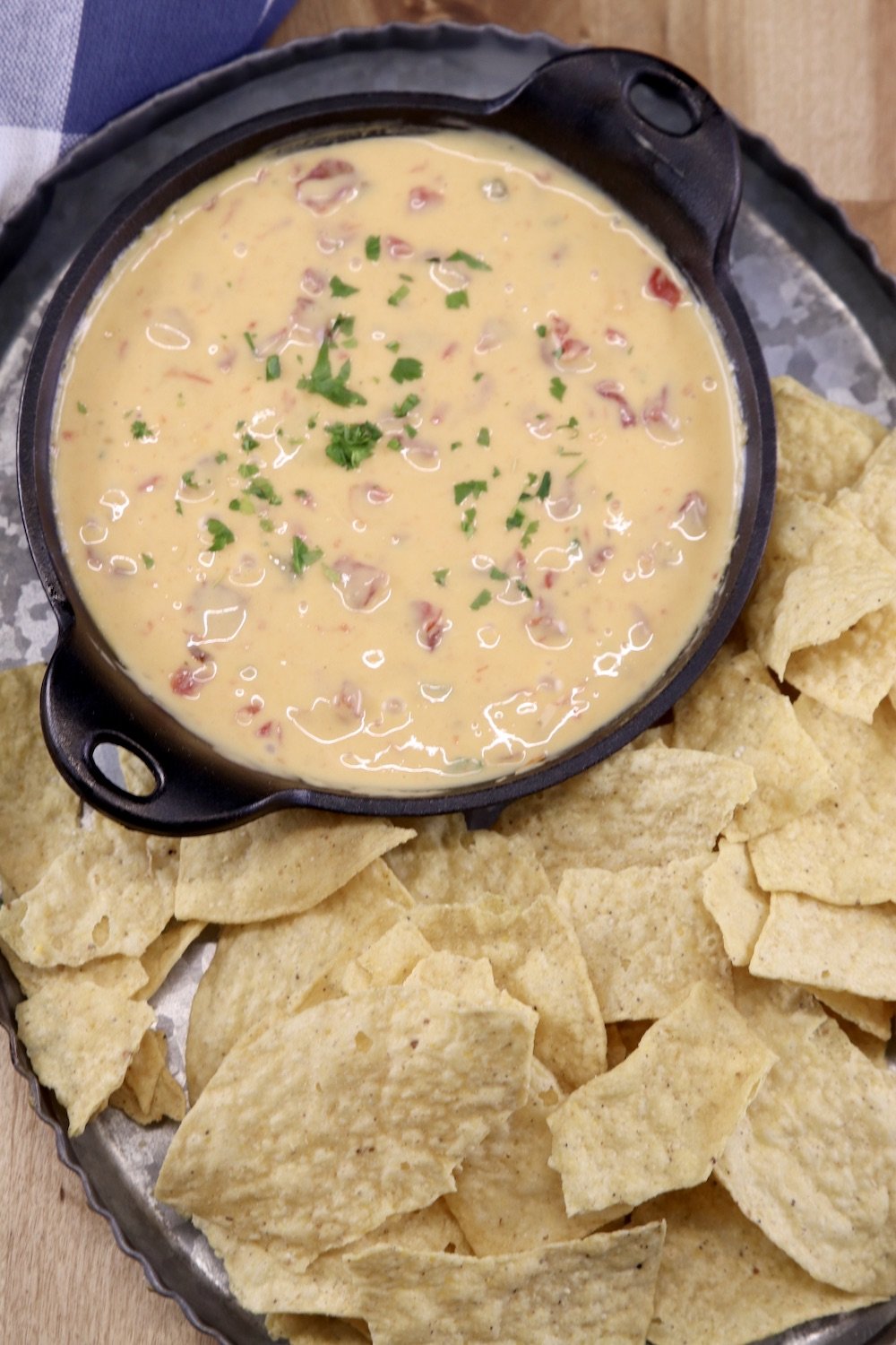 Cheese dip in a small cast iron skillet with tortilla chips on a platter