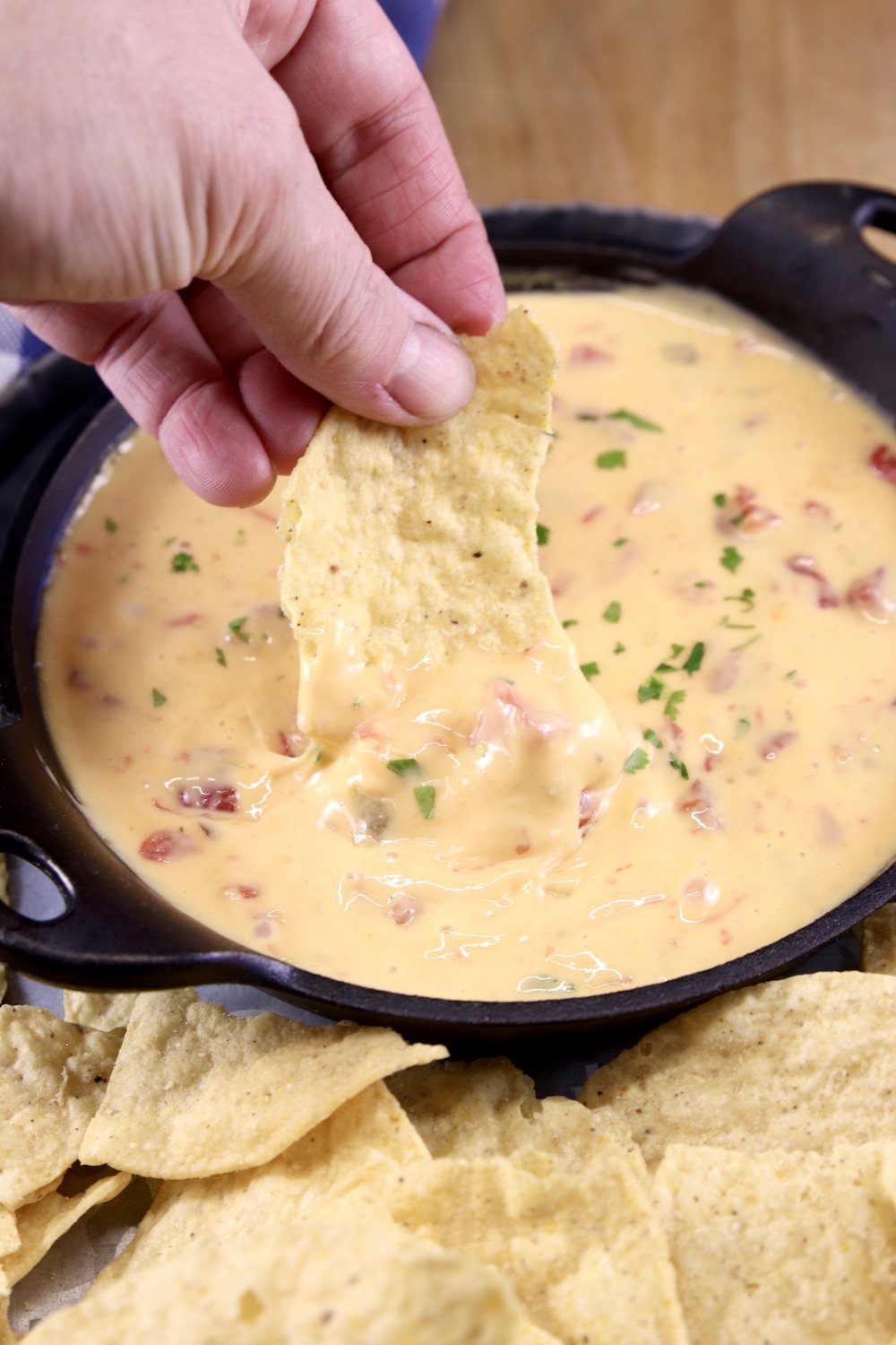 Tortilla chip dipping int cast iron skillet of cheese dip