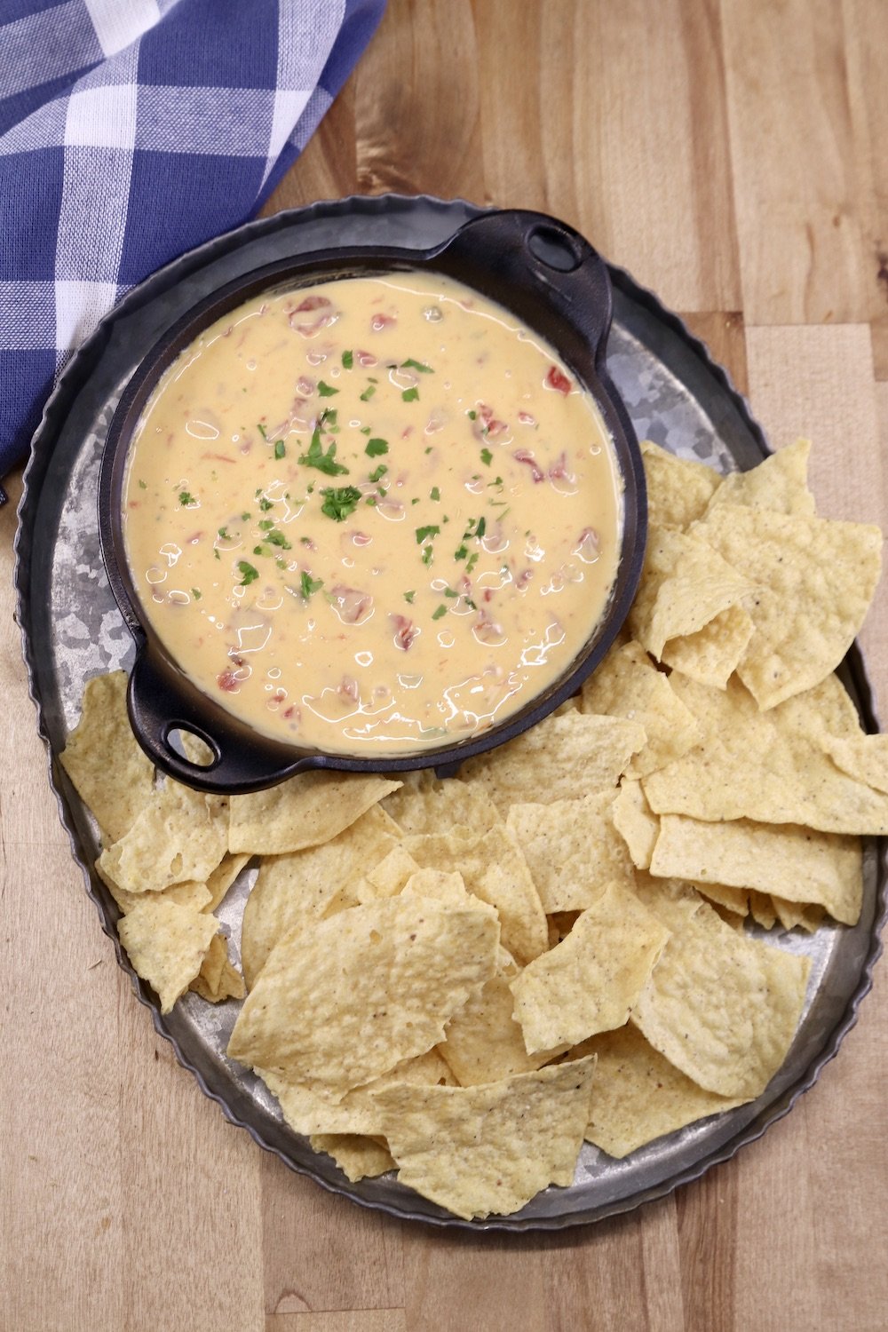 Platter with tortilla chips and cast iron skillet of Cheese Dip