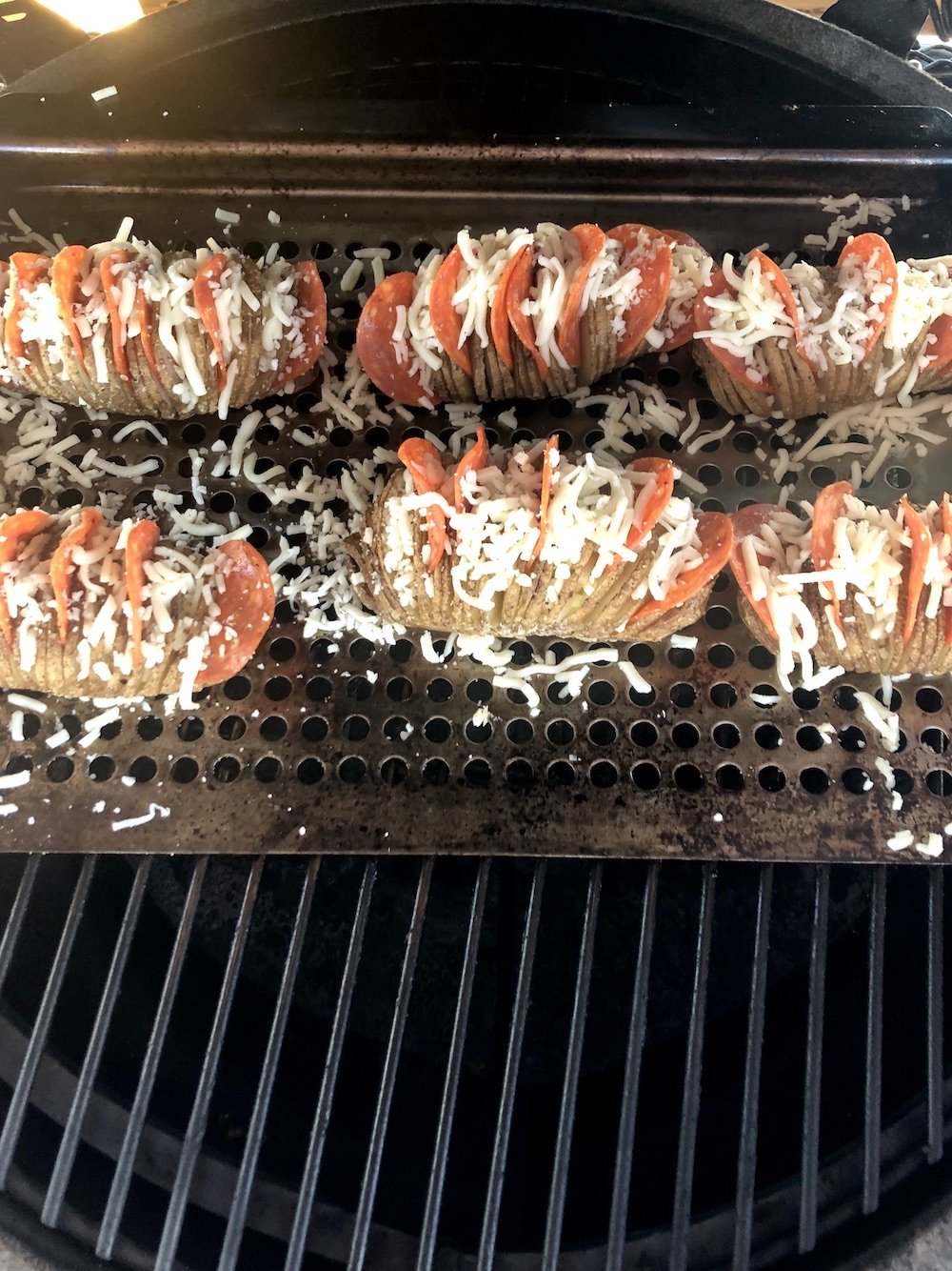 Grill pan of pizza stuffed potatoes on a grill