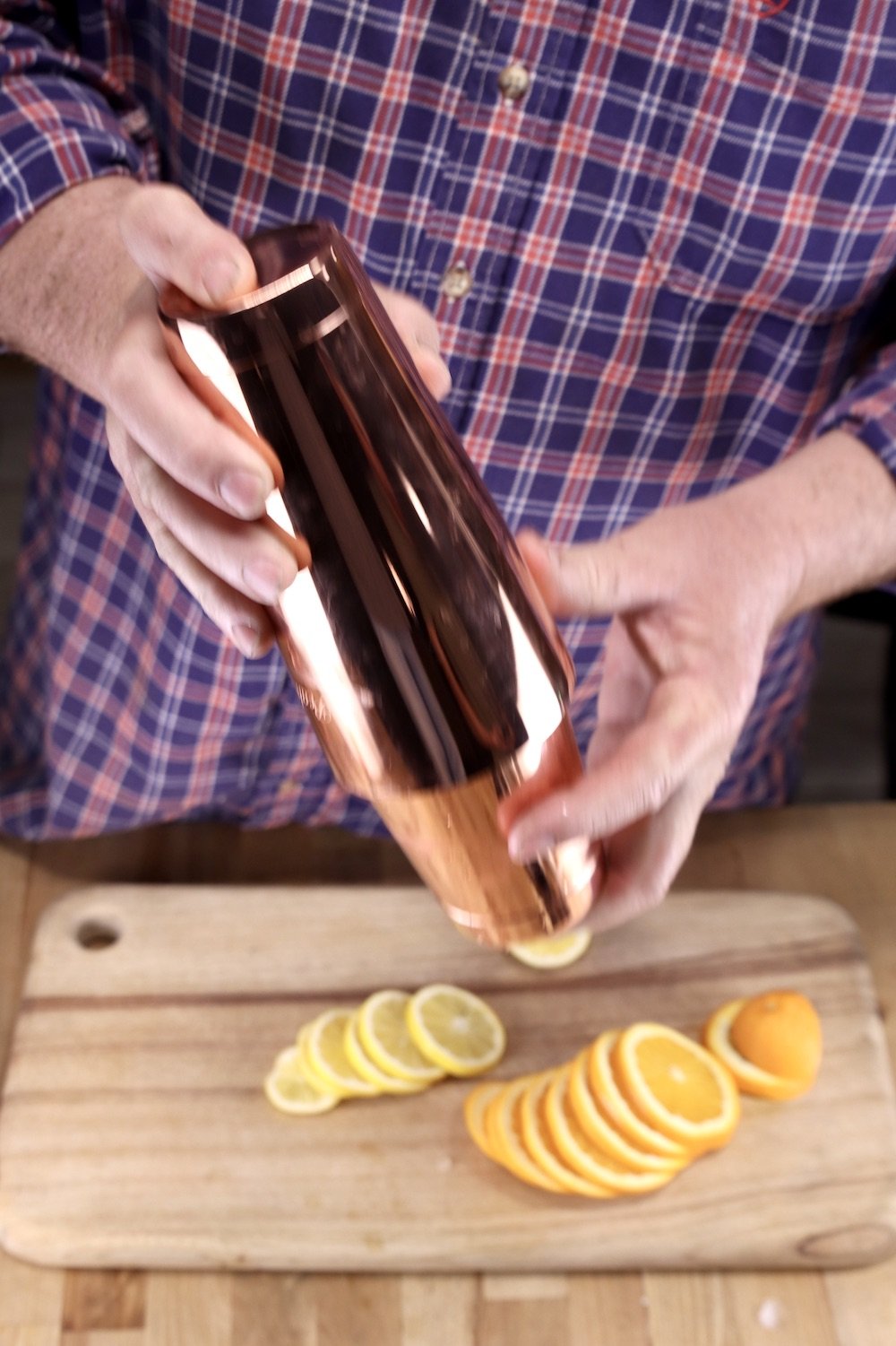 man shaking a copper cocktail shaker