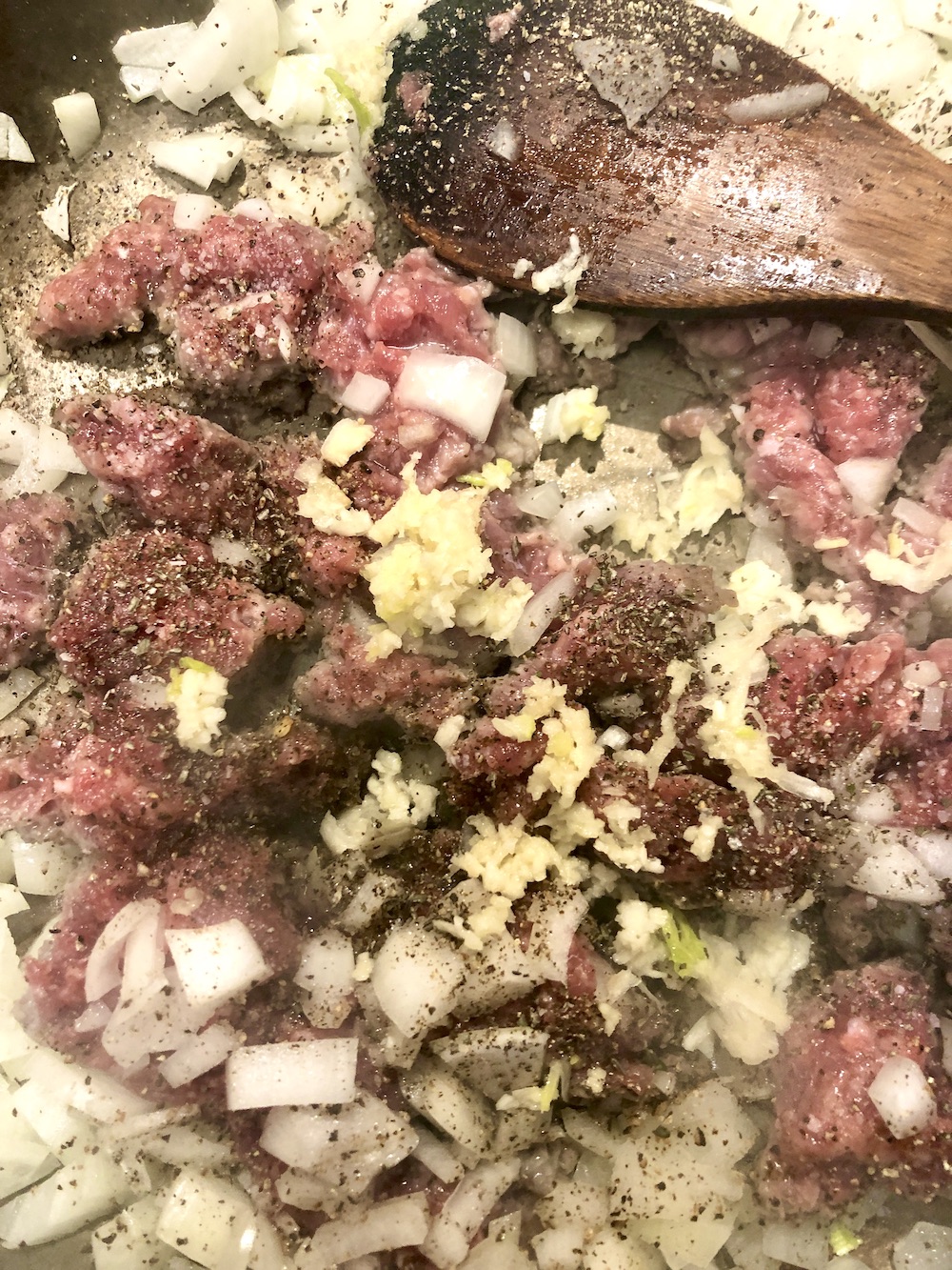 skillet with sausage, onions, garlic -stirring with wood spoon