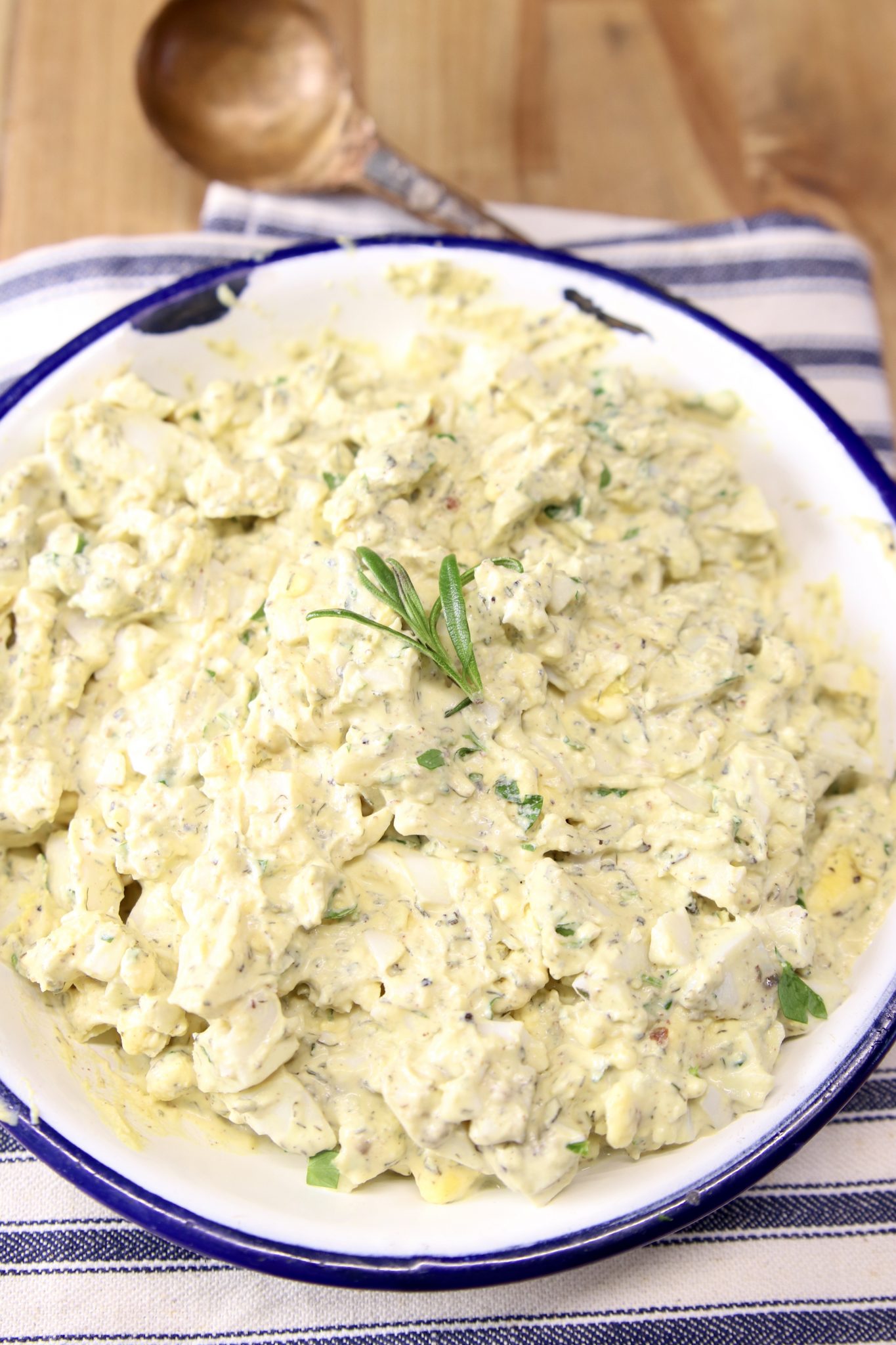 Egg salad in a bowl with sprig of rosemary