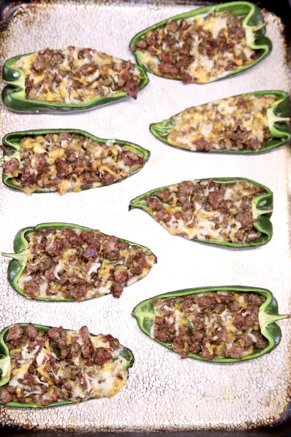 baked poblano peppers with sausage and cheese stuffing on a sheet pan