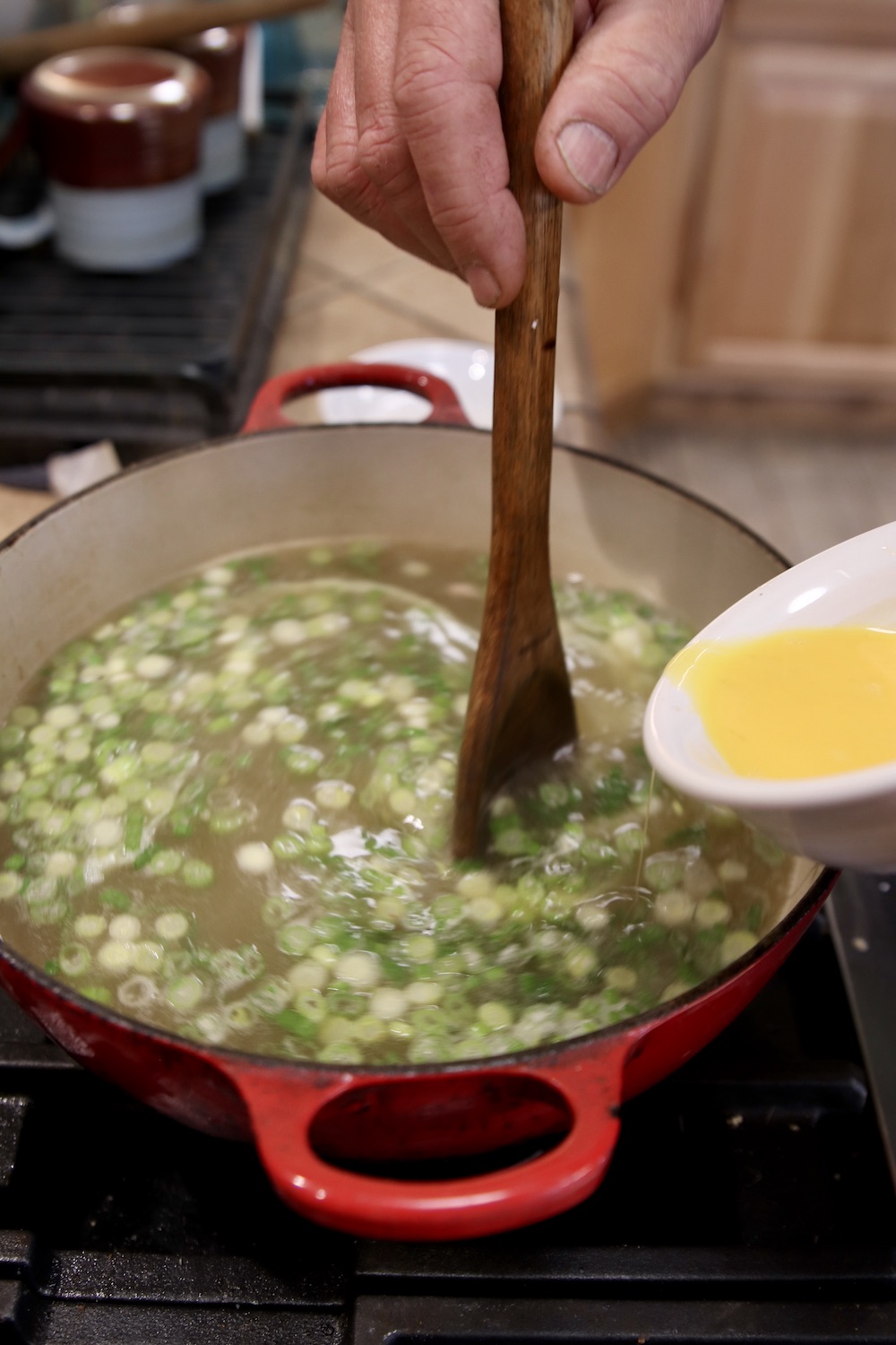 pouring beaten egg into hot broth