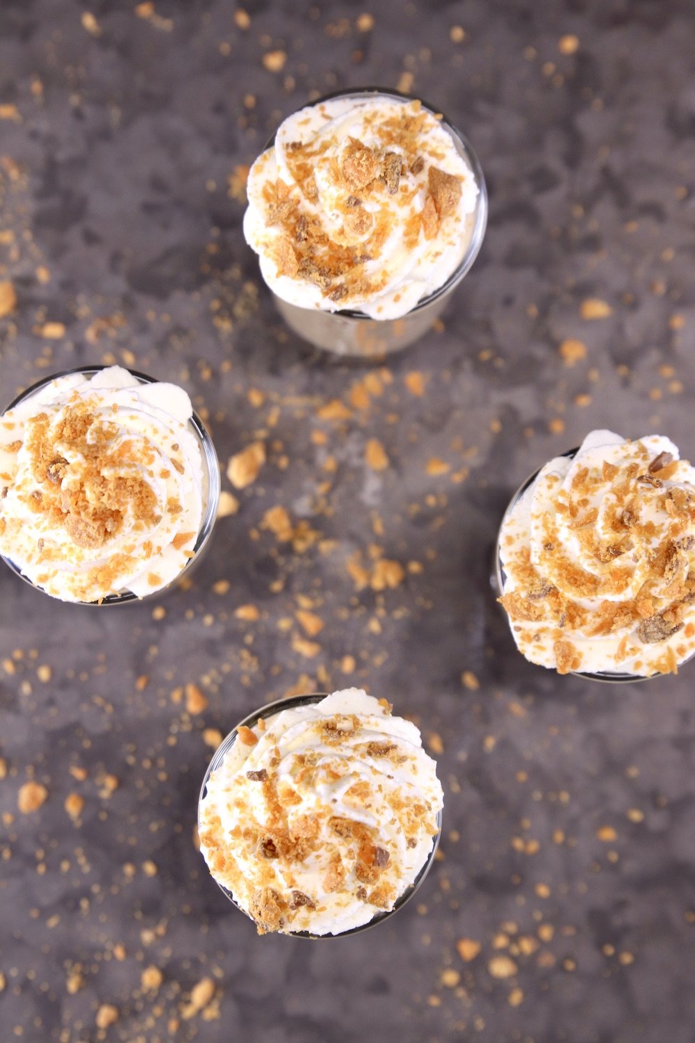overhead view of no bake cheesecakes topped with whipped cream and crushed Butterfingers
