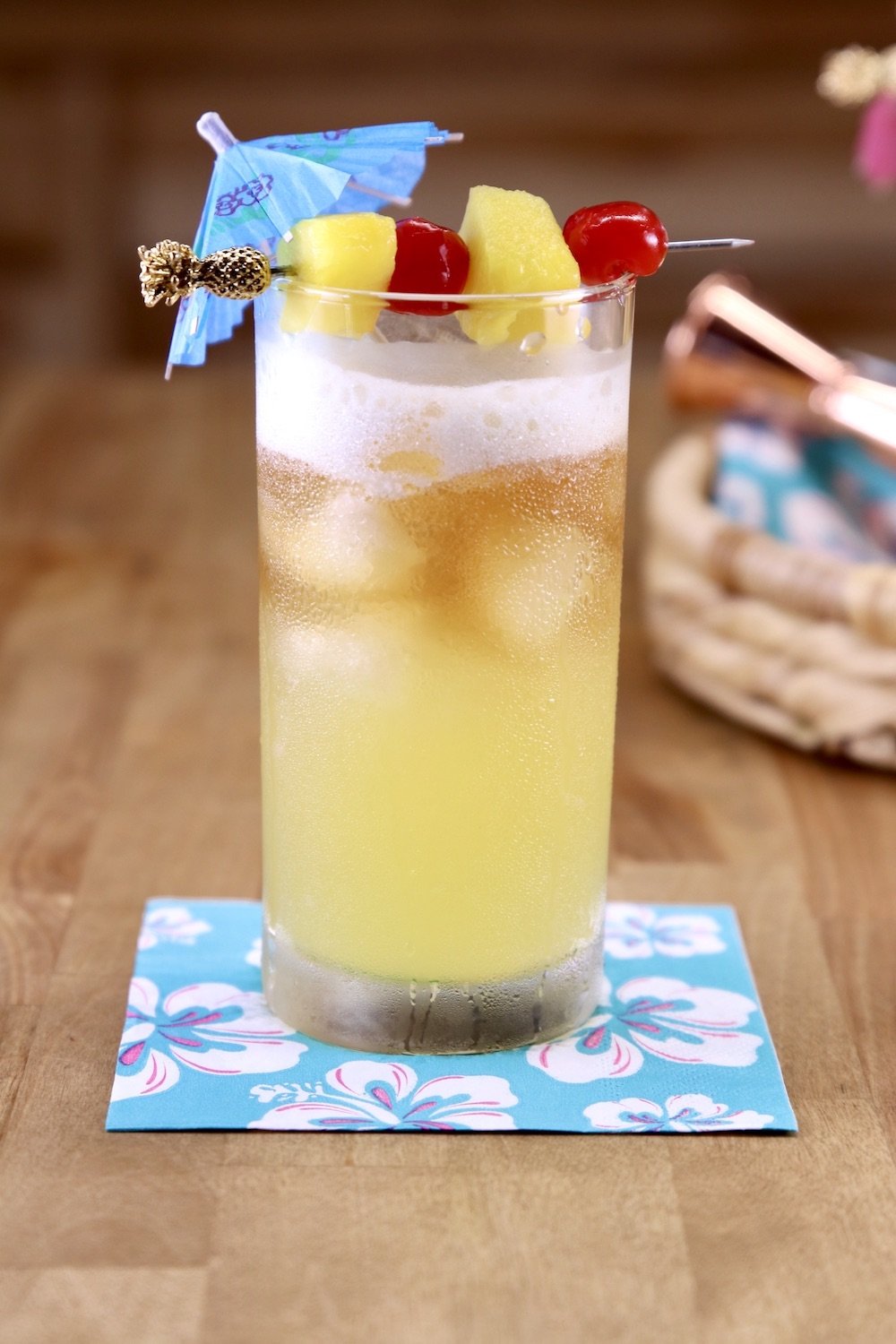 Mai Tai Cocktail with drink umbrella, pineapple cherry garnish in a collins glass