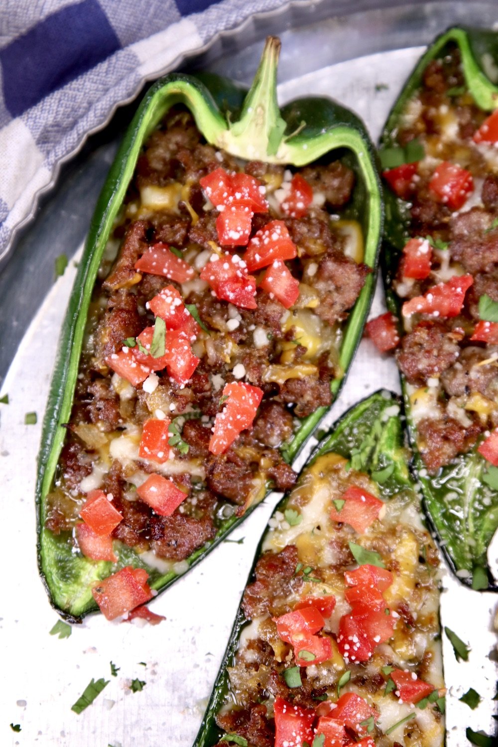 Stuffed poblano peppers with sausage, cheese and tomatoes on a platter