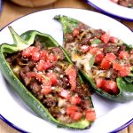 Sausage & Cheese Stuffed Poblano Peppers topped with diced tomatoes on a plate